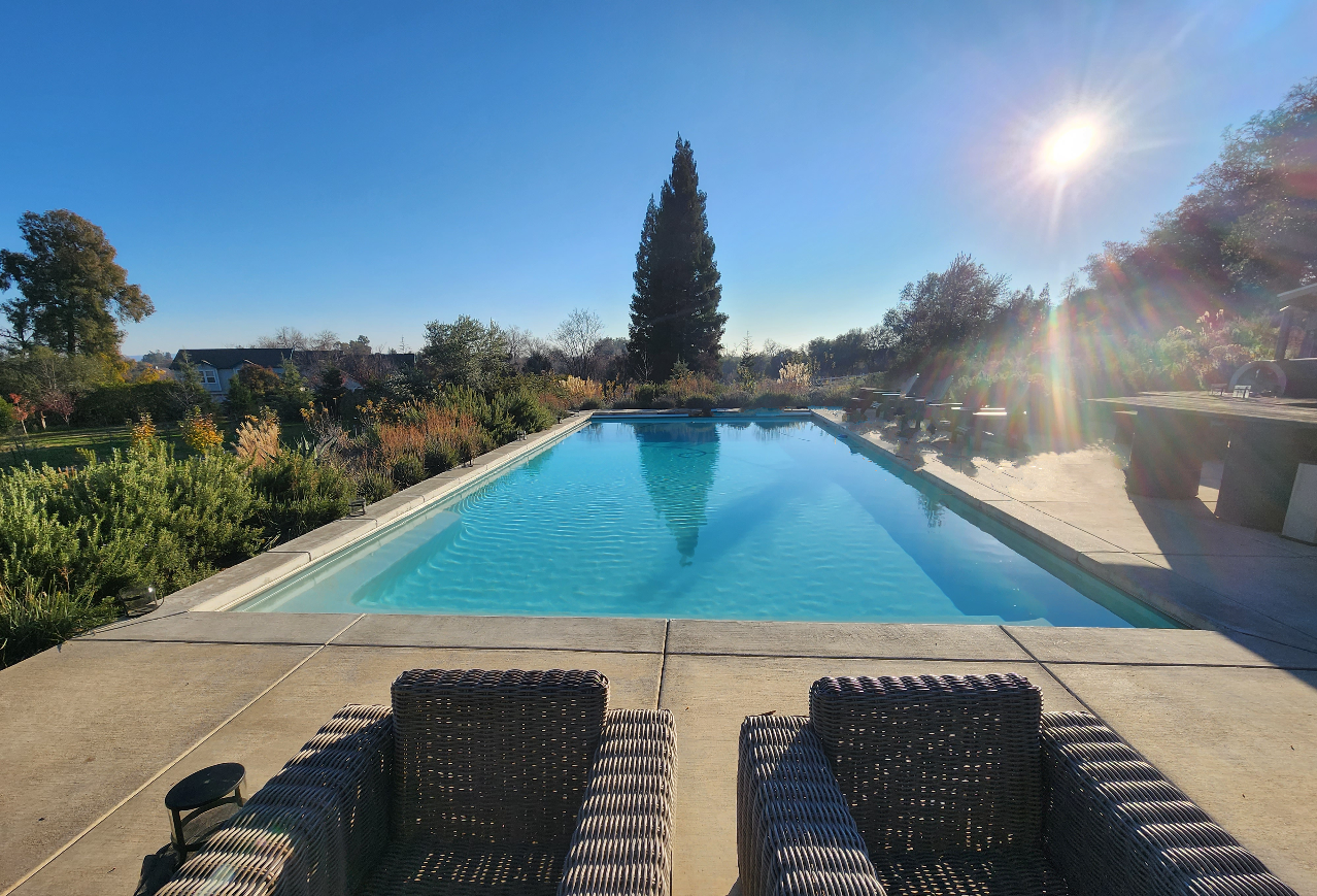 Rectangular pool with automatic pool cover and concrete coping and decking.