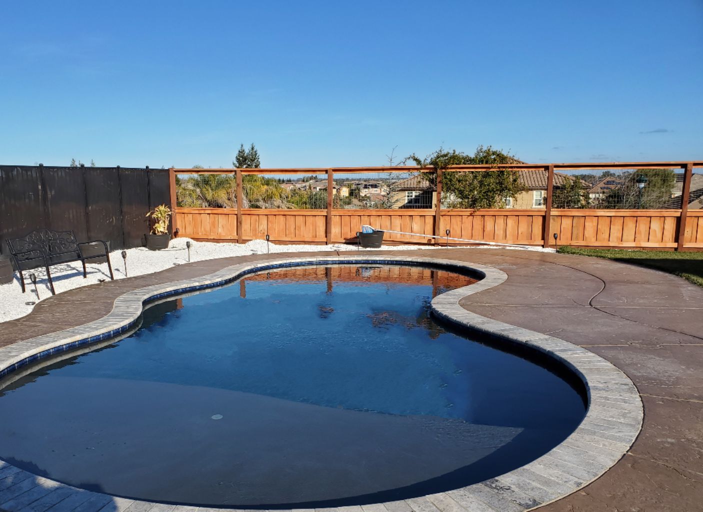 Freeform shaped pool with a large Cabo shelf and travertine stone coping