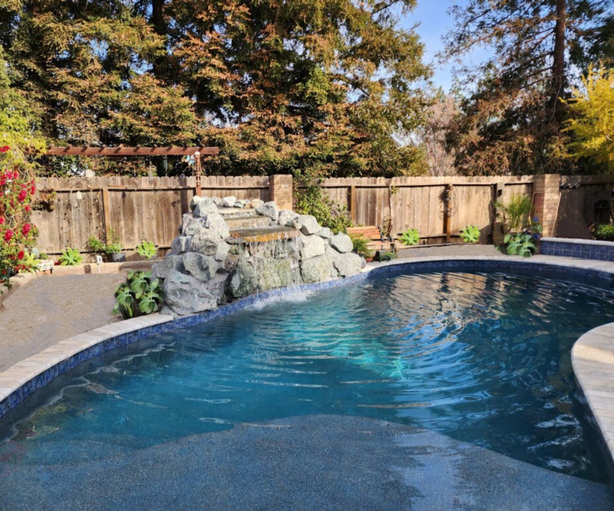 Freeform shaped pool with a rock waterfall and a Cabo shelf